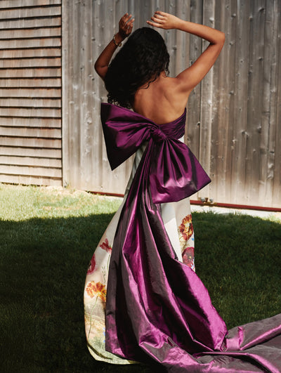 A model has her back turned to the camera showcasing bow detailing at the back of an Oscar de la Renta gown. 