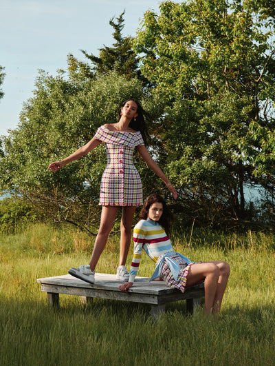 Two models are seen posing on a block of wood in the middle of a field in Oscar de la Renta tweed ready-to-wear styles. 