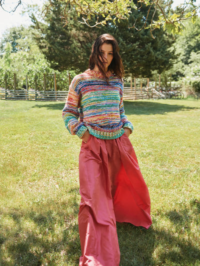 A model is seen posing outside in an Oscar de la Renta striped sweater and wide leg pink trousers. 