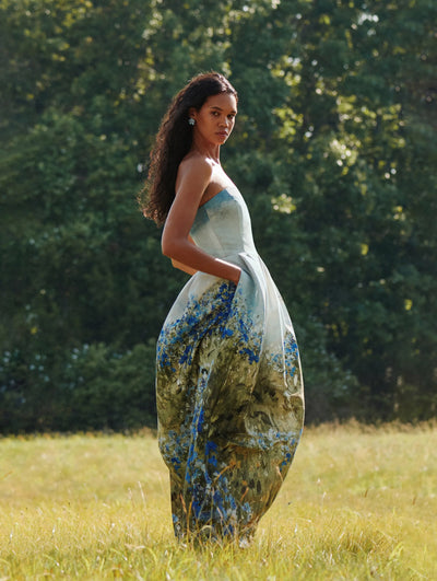 A model is seen posing in a field of grass wearing an Oscar de la Renta gown. 