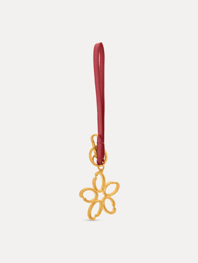 Gold O Flower Wristlet Key Chain with a five-petal open flower that hangs from a deep red leather loop strap, connected by a small gold ring and clasp. Side View. 