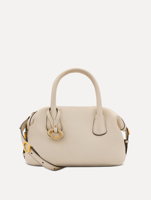 The Mini Dahlia leather handbag in ivory, with O logo tag around the top handle and a Gold Heart bag charm on the other side. Front View
