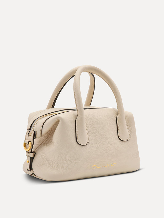 The Mini Dahlia leather handbag in ivory, with O logo tag around the top handle and a Gold Heart bag charm on the other side. Side View