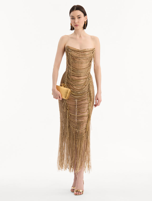 The model is wearing the Knot Minaudière in Gold. Full-Body View.