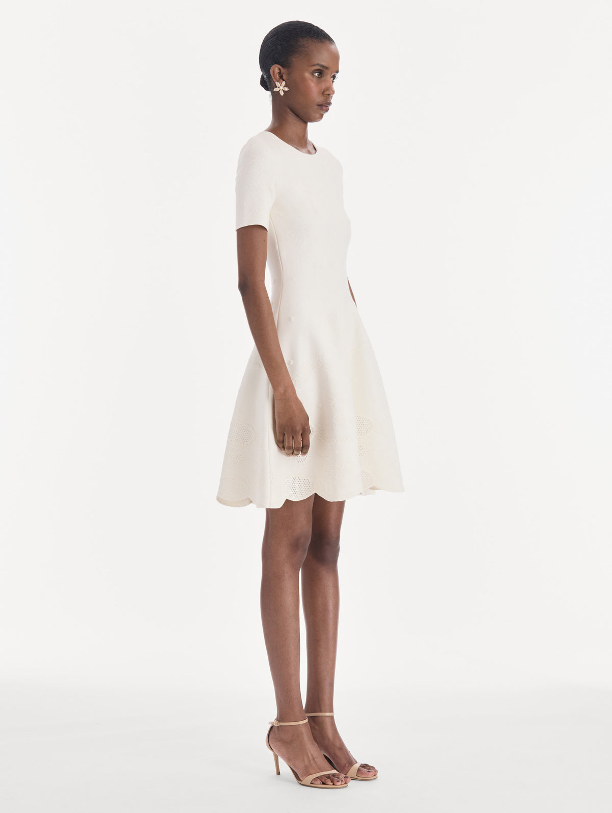 The model is wearing a fit and flare knit jacquard dress. Side view.