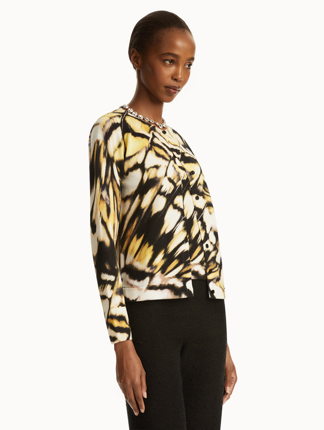 Abstract butterfly print in black, yellow, and white cardigan, paired with black pants. Side view