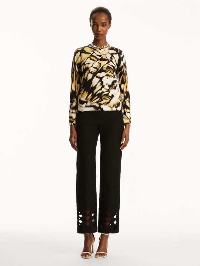 Abstract butterfly print in black, yellow, and white cardigan, paired with black pants. Front view