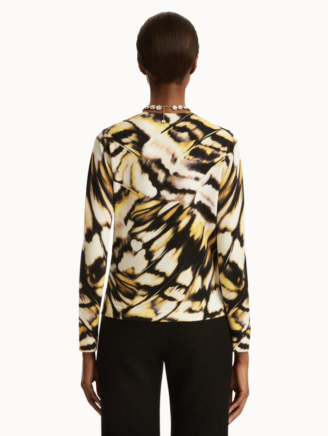 Abstract butterfly print in black, yellow, and white cardigan, paired with black pants. Back view