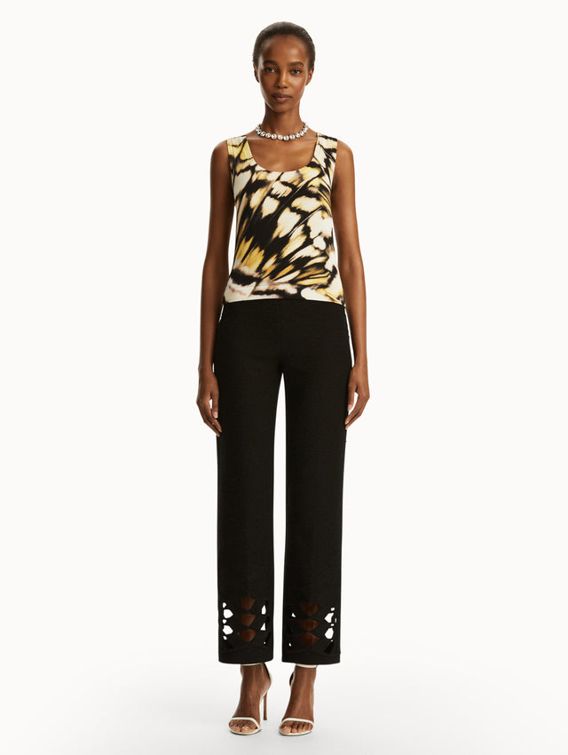 Model wearing Abstract butterfly print in yellow, black, and white tank, paired with black pants. Front view.