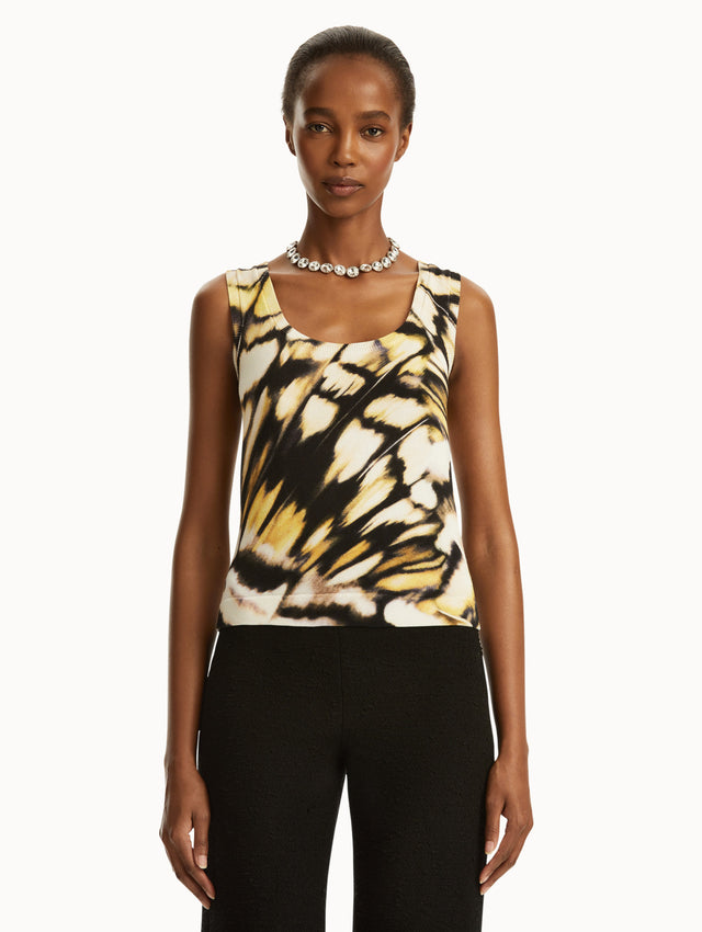 Model wearing Abstract butterfly print in yellow, black, and white tank, paired with black pants. Front view.