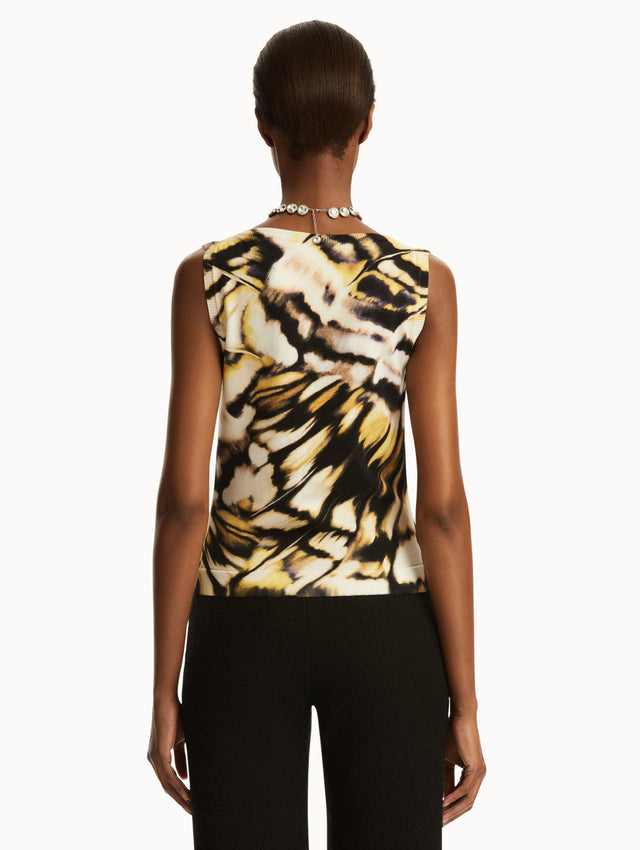 Model wearing Abstract butterfly print in yellow, black, and white tank, paired with black pants. Back view.