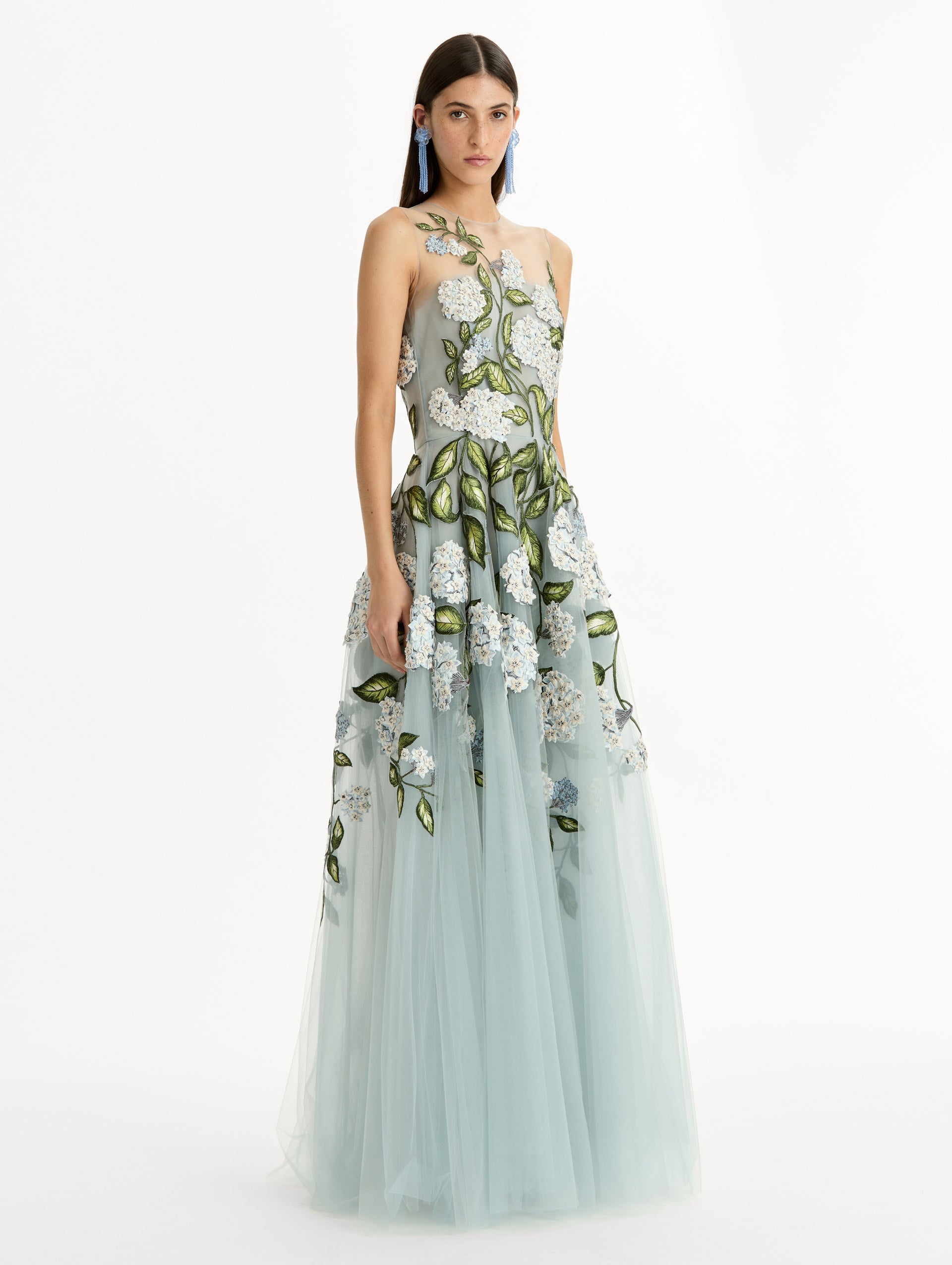 Sheer halter neck gown with porcelain flower embroidery blooming across blue illusion tulle skirt. Side View. 