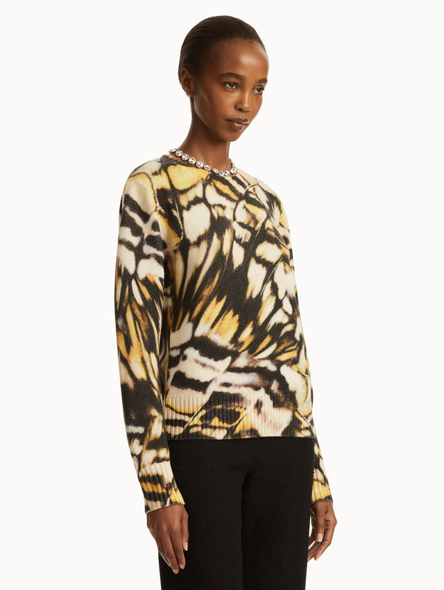 Abstract butterfly print in shades of black/brown, yellow, and white pullover, paired with black pants. Side view