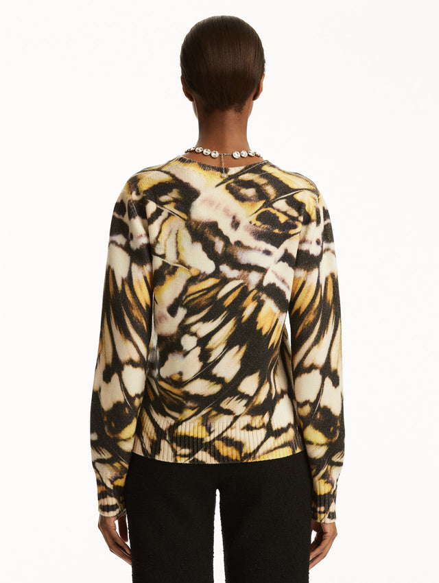 Abstract butterfly print in shades of black/brown, yellow, and white pullover, paired with black pants. back view