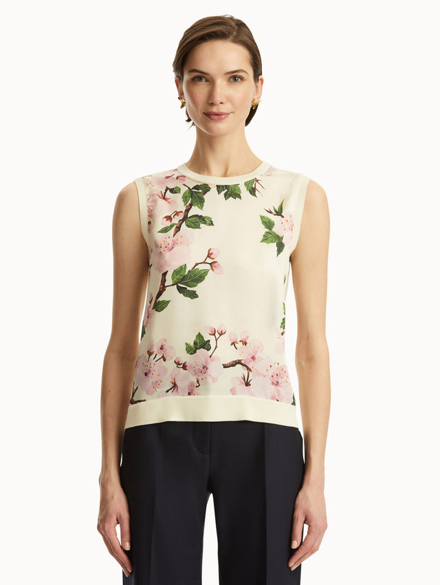 White tank with pink cherry blossoms printed, paired with black pants. Front view
