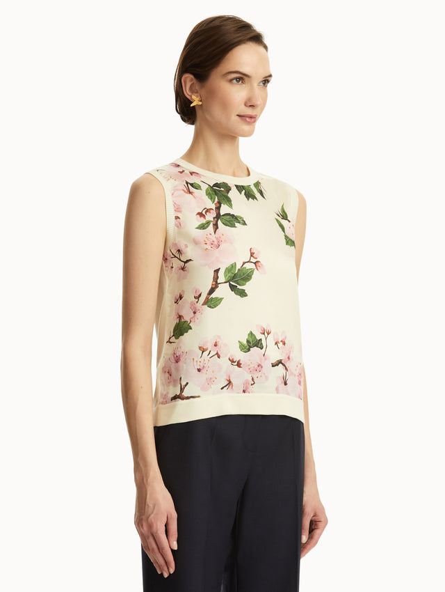 White tank with pink cherry blossoms printed, paired with black pants. Side view