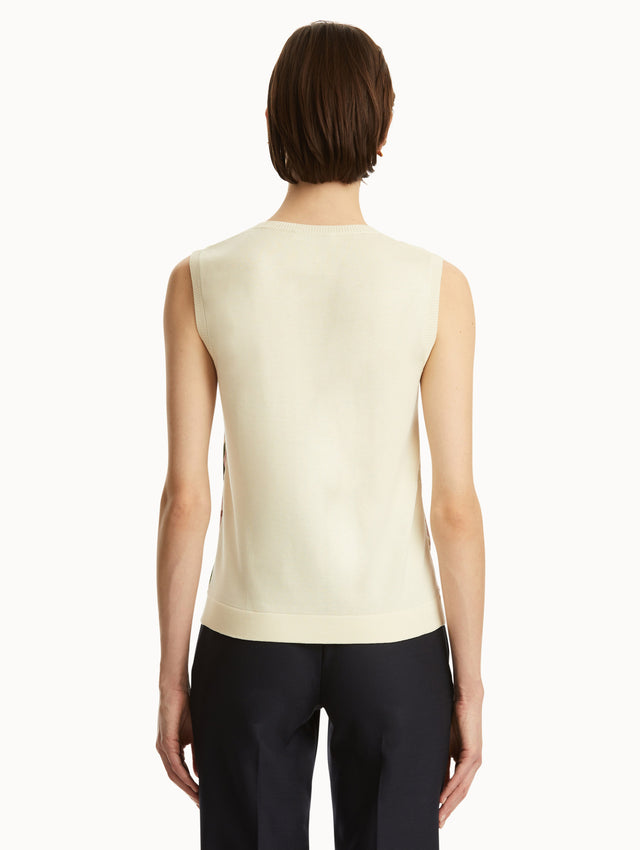 White tank with pink cherry blossoms printed in the front, paired with black pants. Back view