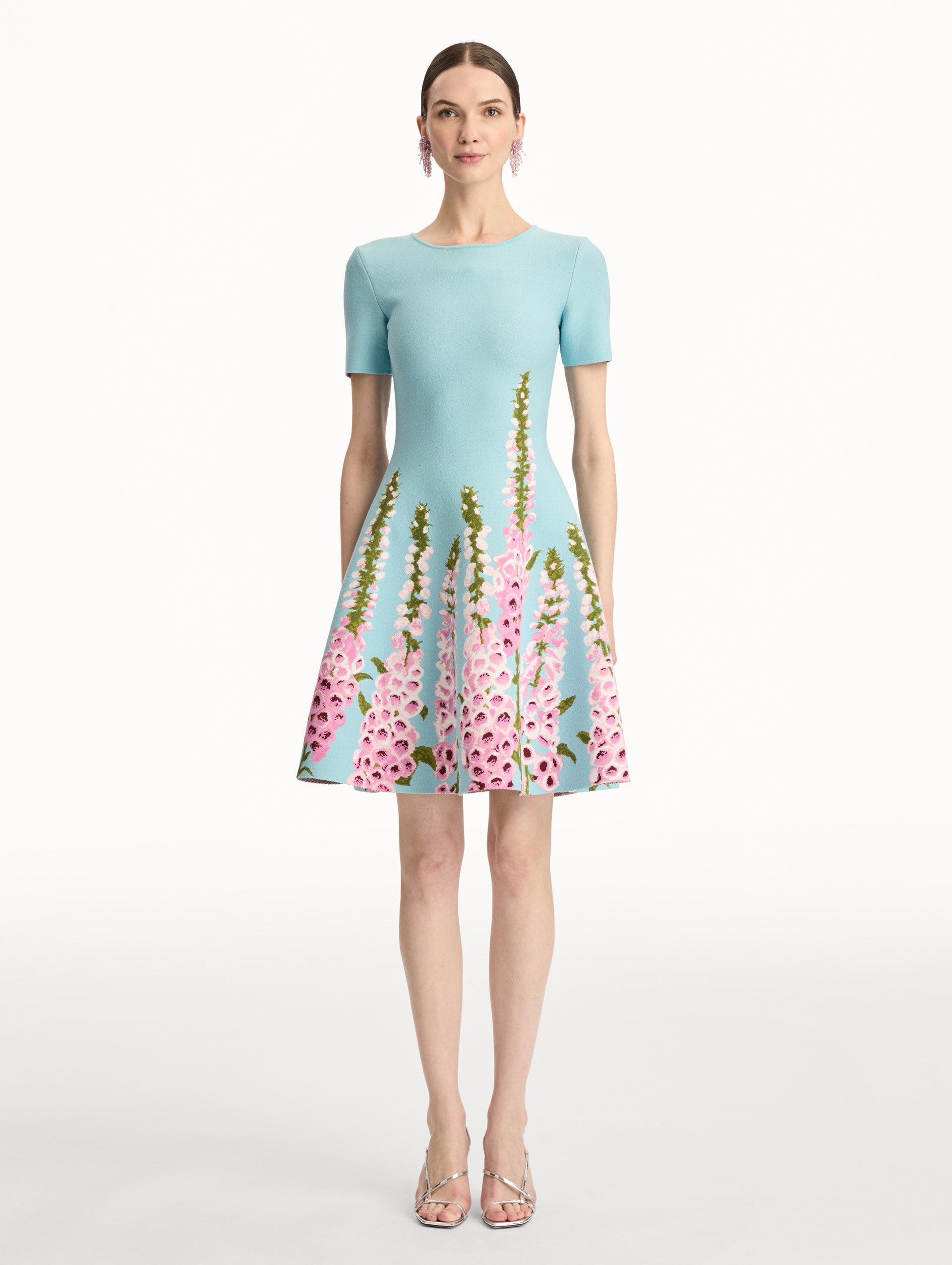 Blue Foxglove Jacquard Knit Dress with short sleeves, a fitted bodice, flared skirt, and pink foxglove floral embroidery cascading from the hem upward. Front View.