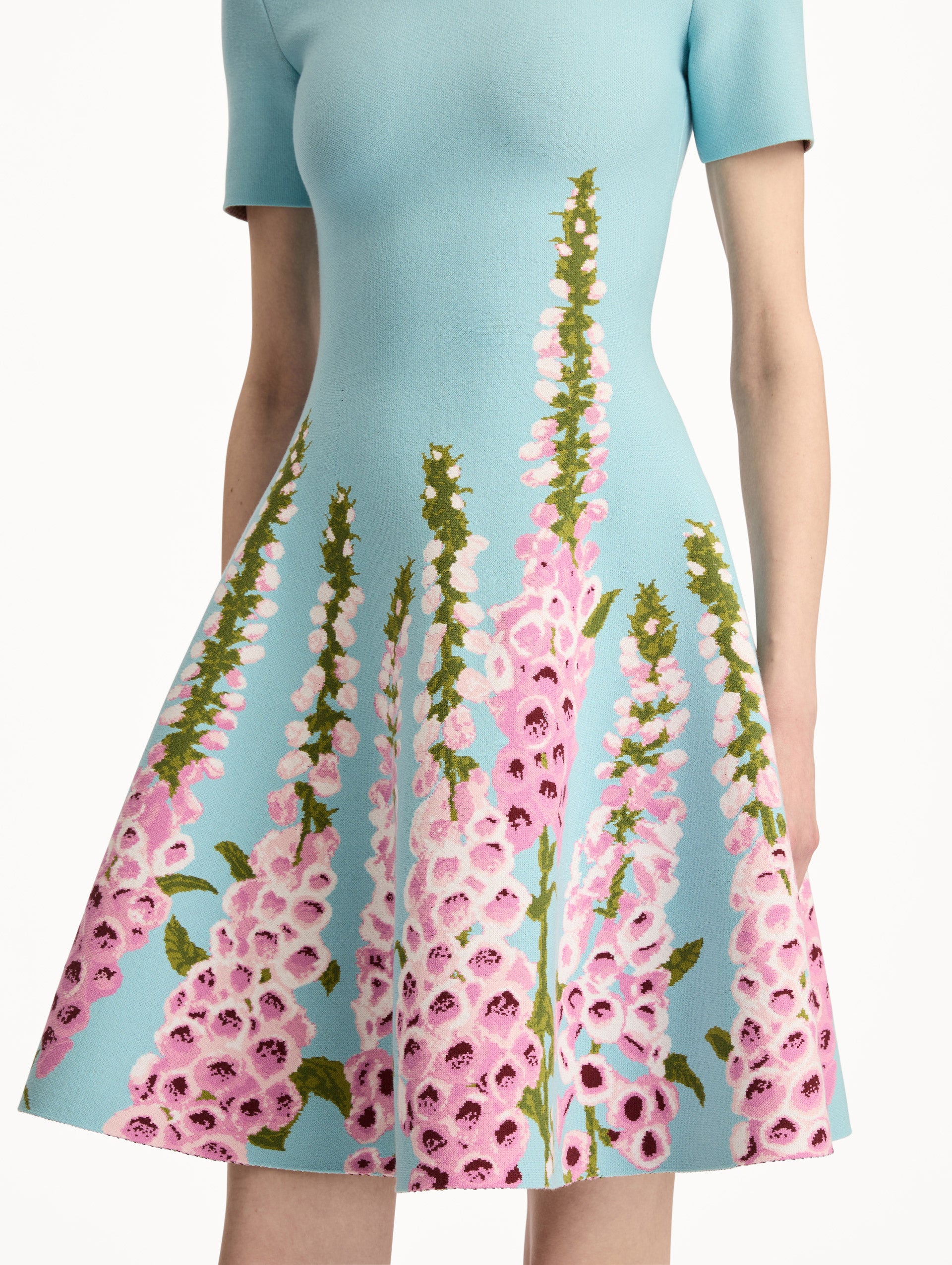 Blue Foxglove Jacquard Knit Dress with short sleeves, a fitted bodice, flared skirt, and pink foxglove floral embroidery cascading from the hem upward. Zoom View.