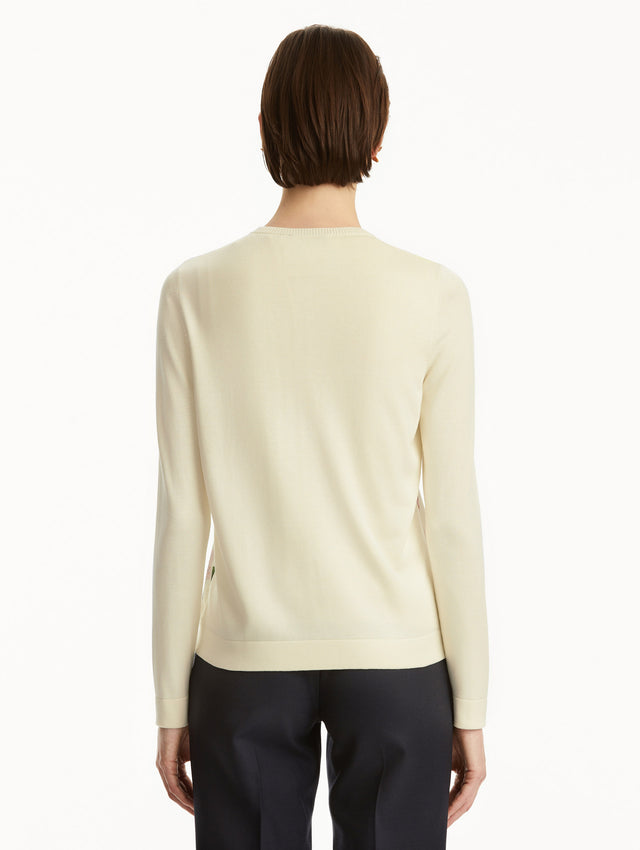 Model wearing white cardigan with pink cherry blossoms, paired with black pants. Back View