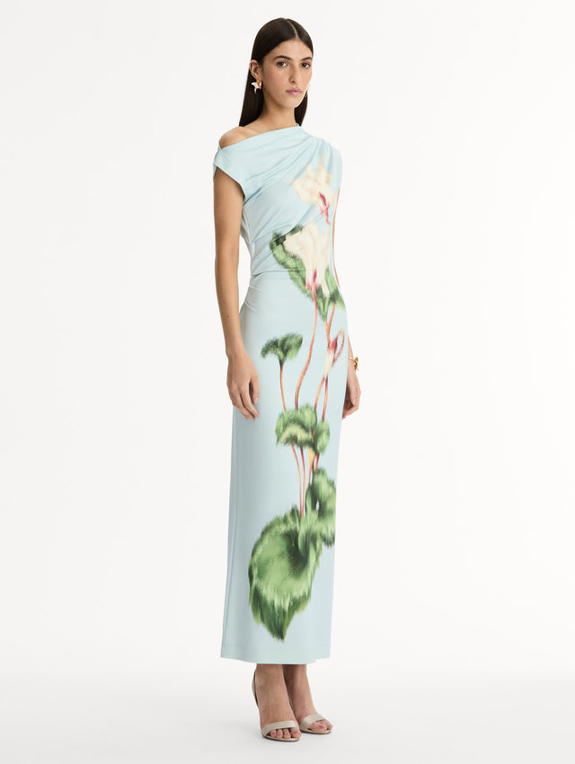 Light blue, ankle length jersey dress. Chiné Cyclamen motif with blurred edges. Asymmetric neckline, off the shoulder. Side view. 