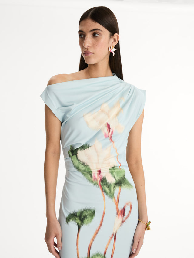 Light blue, ankle length jersey dress. Chiné Cyclamen motif with blurred edges. Asymmetric neckline, off the shoulder. Front view, Close Up. 