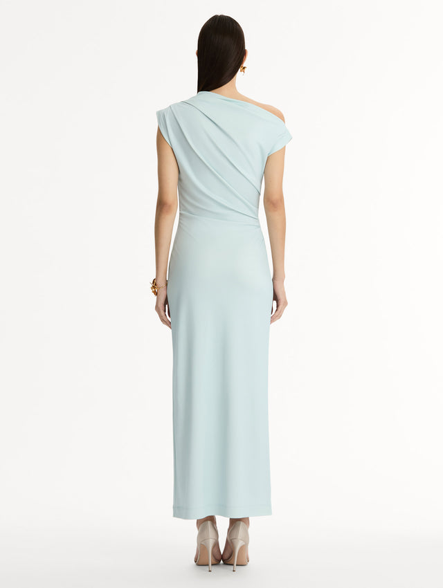 Light blue, ankle length jersey dress. Chiné Cyclamen motif with blurred edges. Asymmetric neckline, off the shoulder. Back view. 