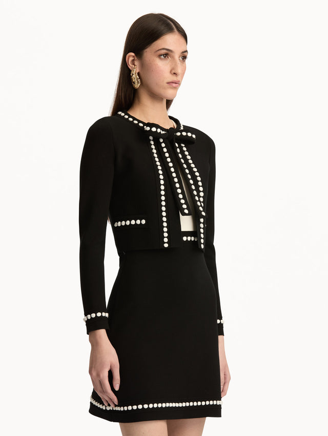 Black and White Bubble Trim Cardigan featuring white beaded trim, long sleeves, and a tie-neck collar. Side View.