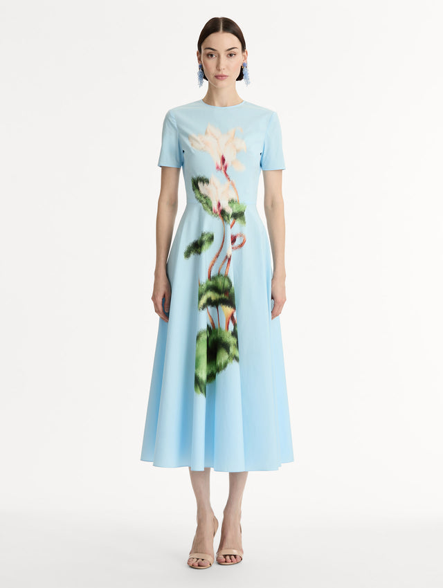 Short sleeve, light blue cotton poplin midi dress. Fitted bodice, full A-line skirt. Chiné Cyclamen motif with blurred, edges. Front View.