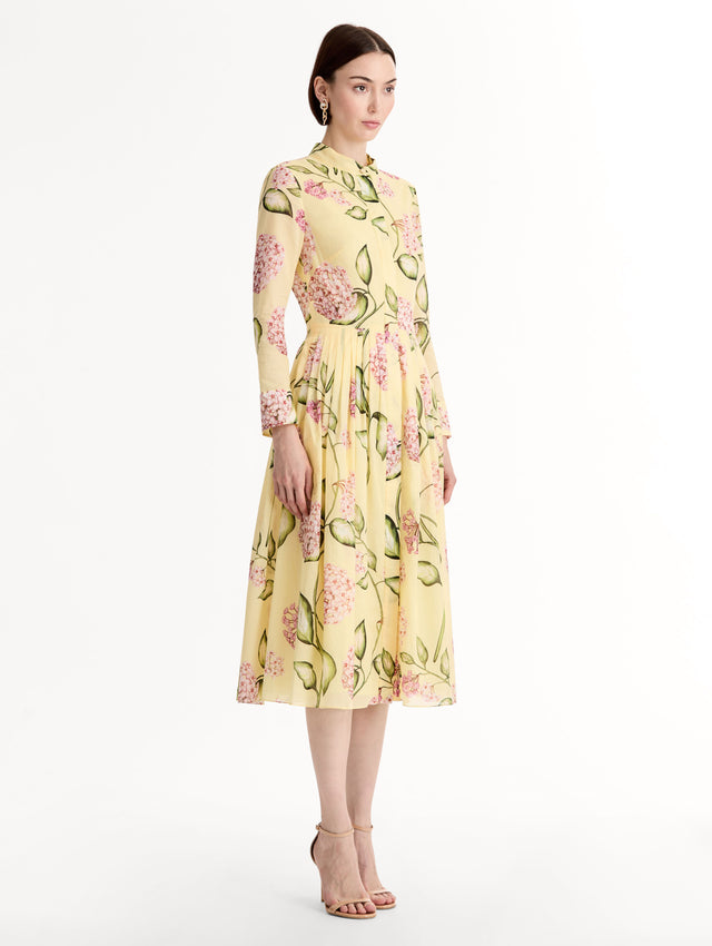 Long-sleeve, yellow cotton poplin midi dress. Porcelain flower print. Pleated silhouette. Concealed button front. Softly structured collar. Side View. 