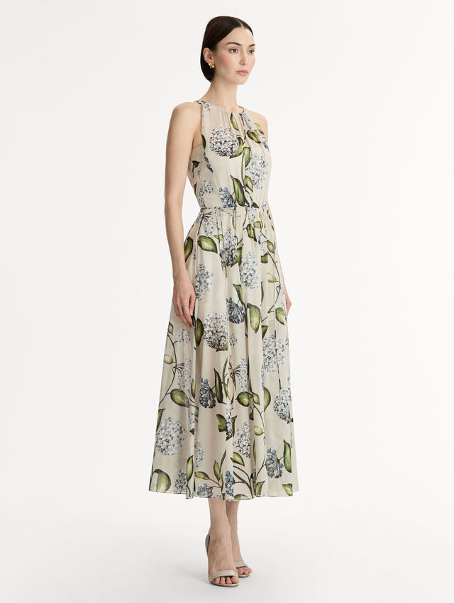 Halter neck, sleeveless, cotton poplin midi dress in off white. Pleated with blue flower print. Subtle bows at waist. Side View.