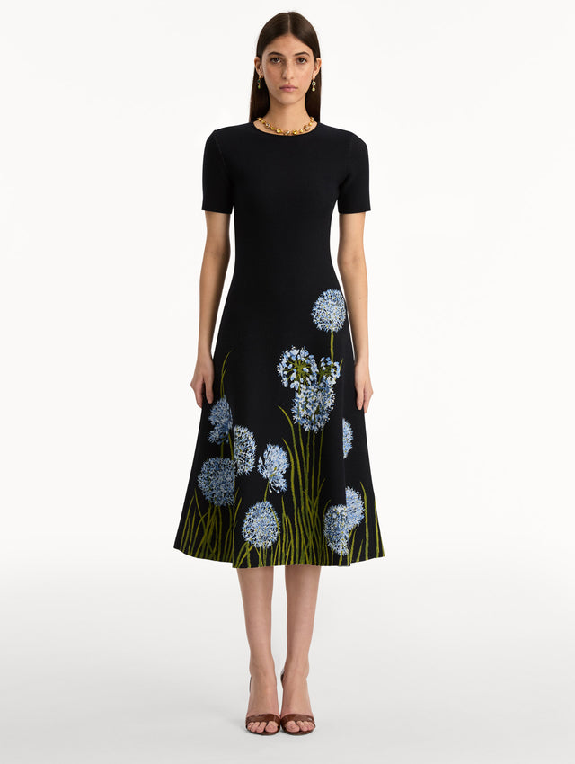 Navy Allium Jacquard Knit Dress featuring blue floral embroidery with green stem detailing along the skirt. Front View.