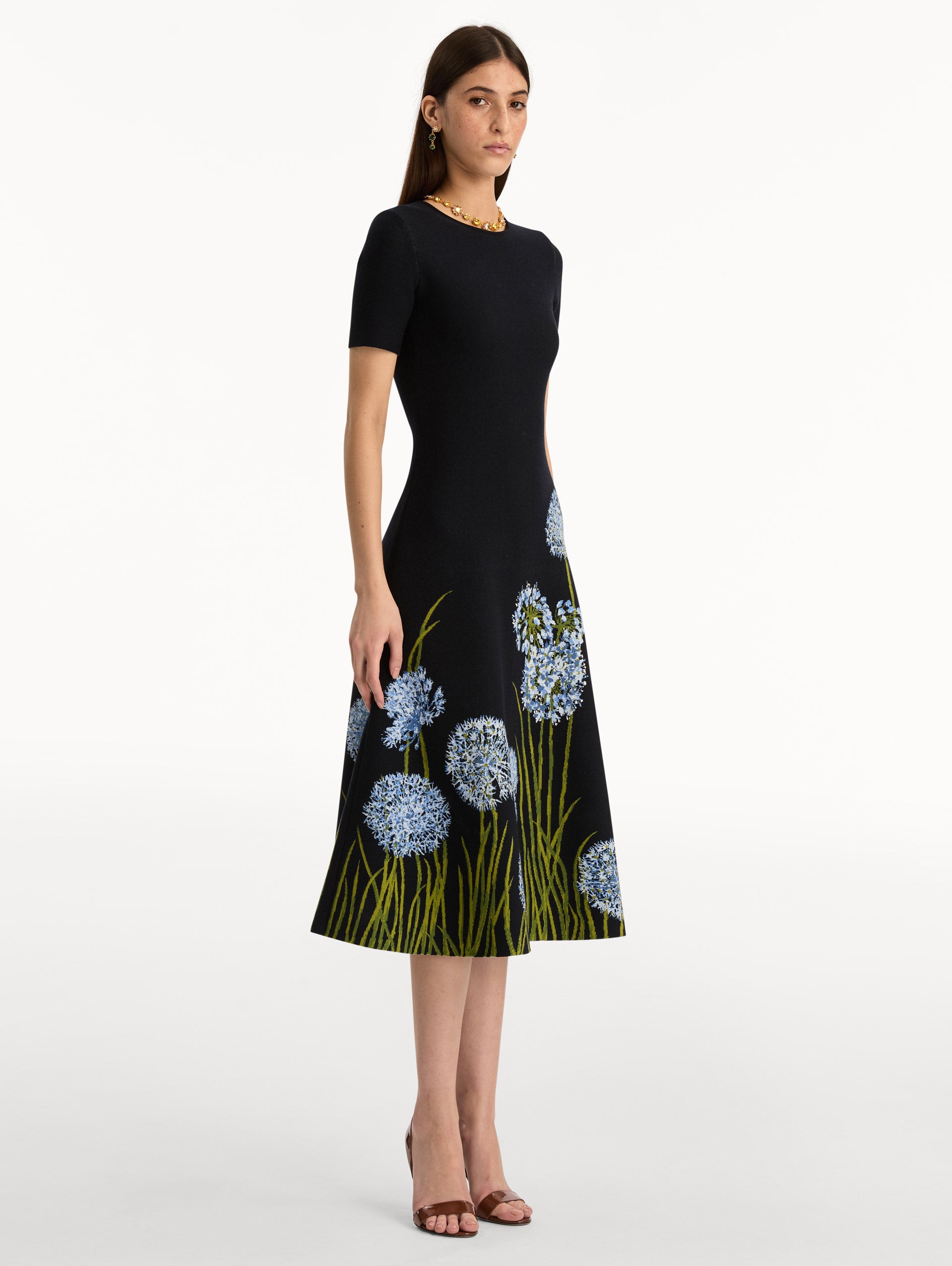 Navy Allium Jacquard Knit Dress featuring blue floral embroidery with green stem detailing along the skirt. Side View.