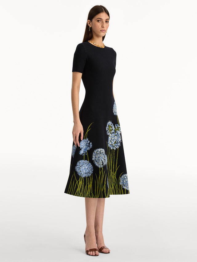 Navy Allium Jacquard Knit Dress featuring blue floral embroidery with green stem detailing along the skirt. Side View.