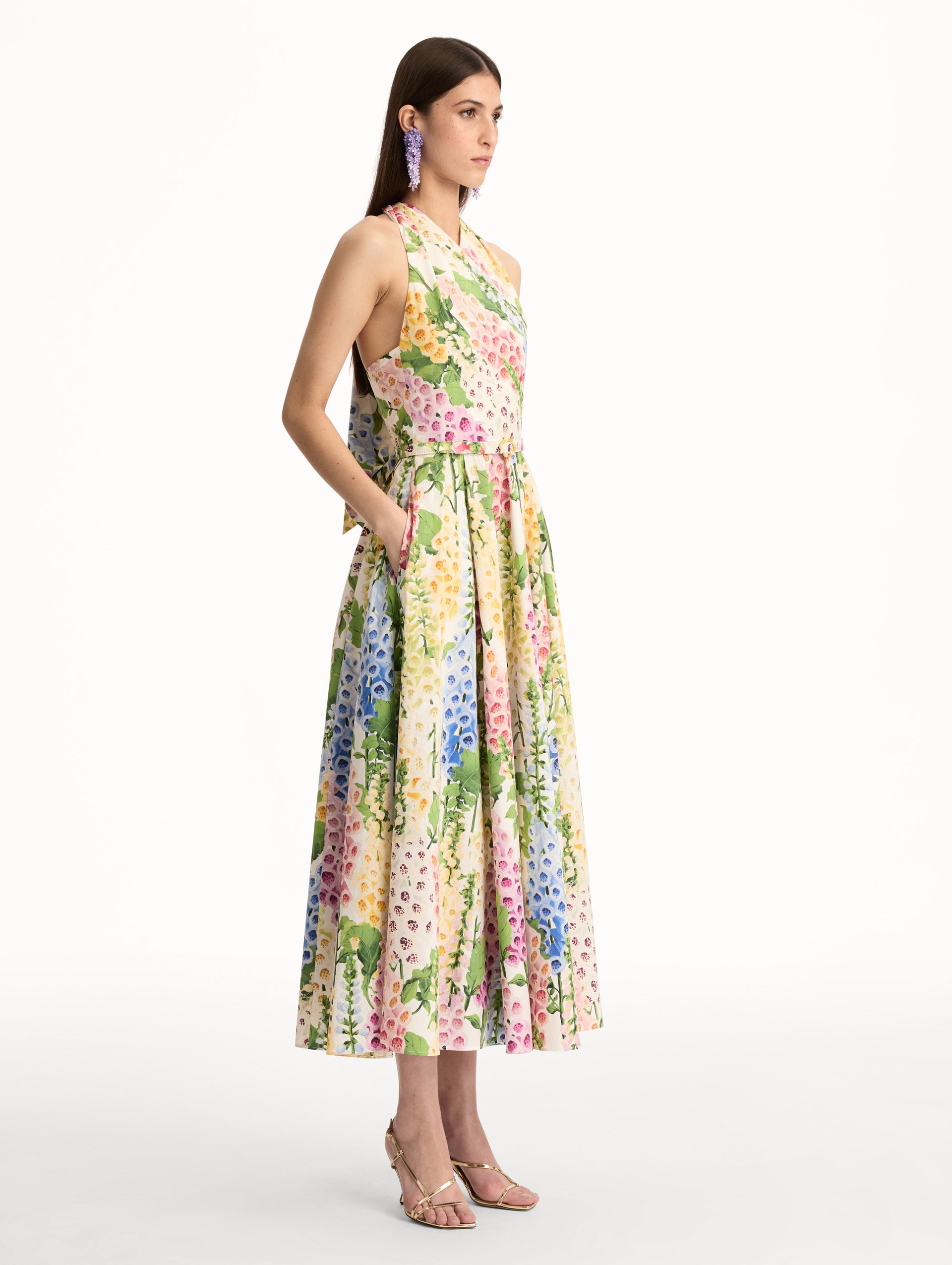 Foxglove Cotton Poplin Halter Dress with a fitted bodice and flowing skirt, featuring a colorful floral print in shades of pink, yellow, blue, and green. Side View.