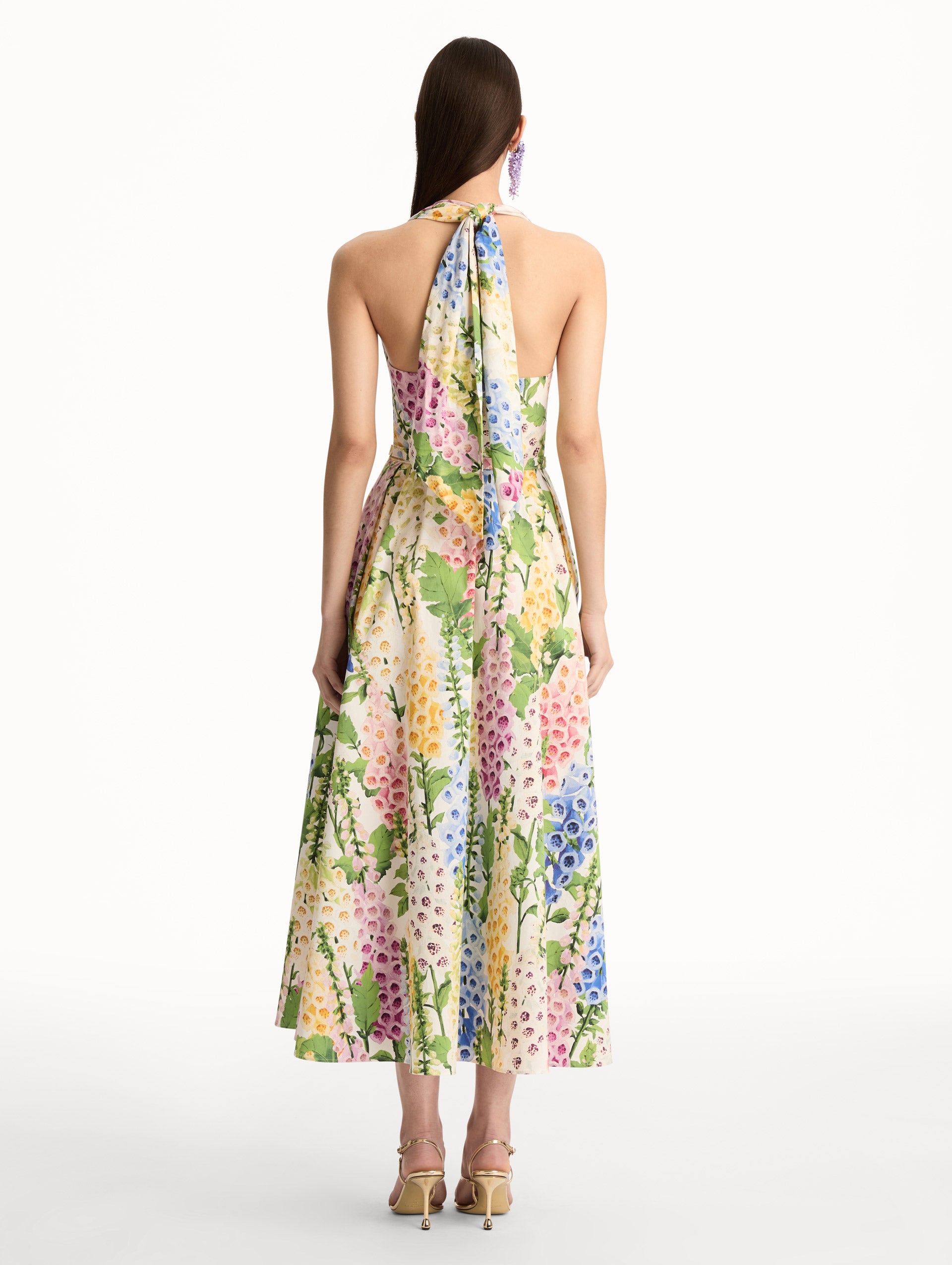 Foxglove Cotton Poplin Halter Dress with a fitted bodice and flowing skirt, featuring a colorful floral print in shades of pink, yellow, blue, and green. Back View.