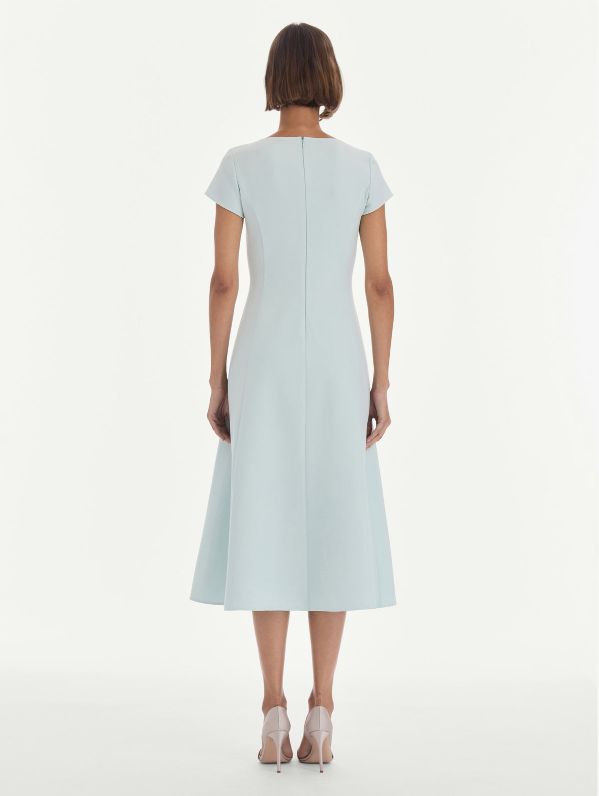 The model is wearing a short sleeve scoop neck stretch wool day dress. Back view.