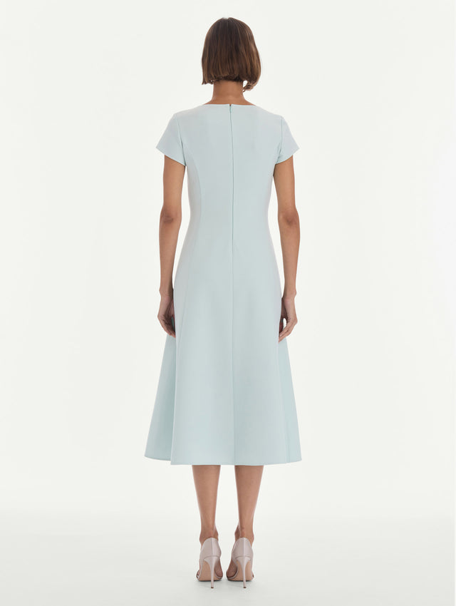 The model is wearing a short sleeve scoop neck stretch wool day dress. Back view.