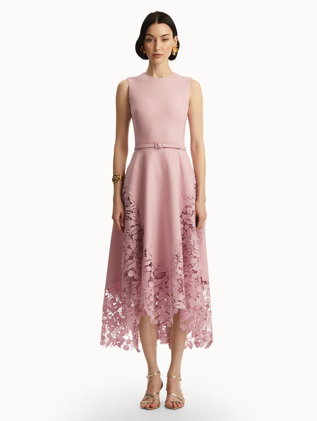 Sleeveless light pink dress with lace detail in the bottom and pink belt around the waist. Front view