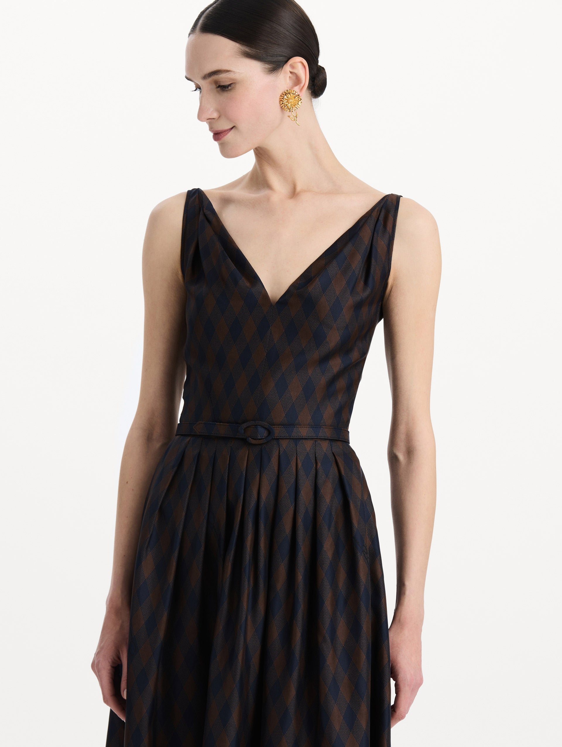 The model is wearing the argyle silk twill dress with a sleeveless silhouette, a V-neckline, and an argyle print in navy and brown. Zoom view. 