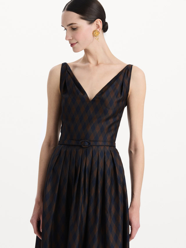 The model is wearing the argyle silk twill dress with a sleeveless silhouette, a V-neckline, and an argyle print in navy and brown. Zoom view. 