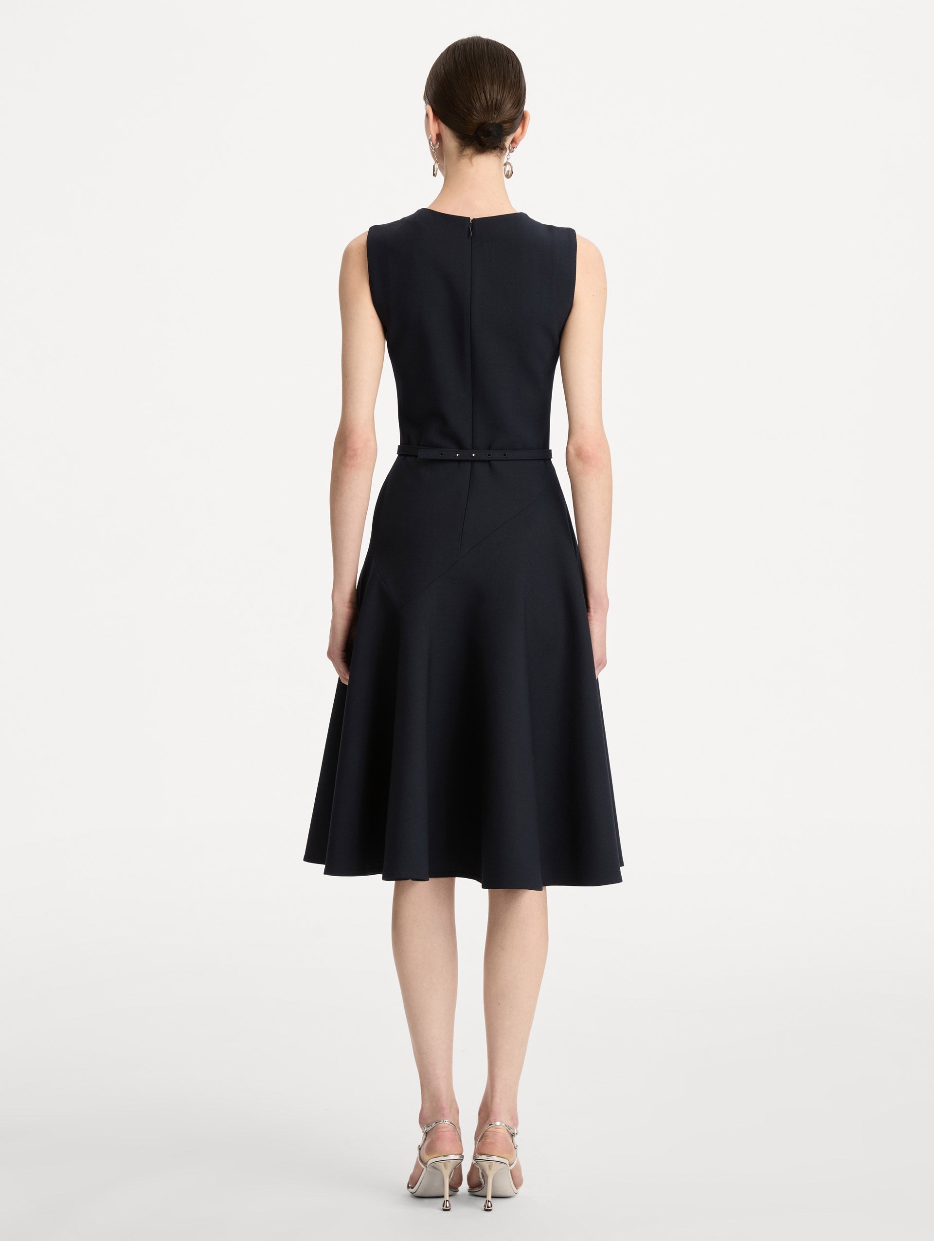 Black Floral Belt Sleeveless Dress featuring a belted waist with a white floral embellishment and a knee-length skirt. Back View.