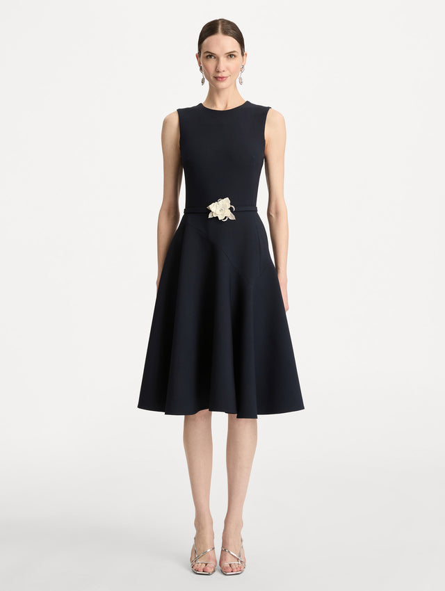 Black Floral Belt Sleeveless Dress featuring a belted waist with a white floral embellishment and a knee-length skirt. Front View.