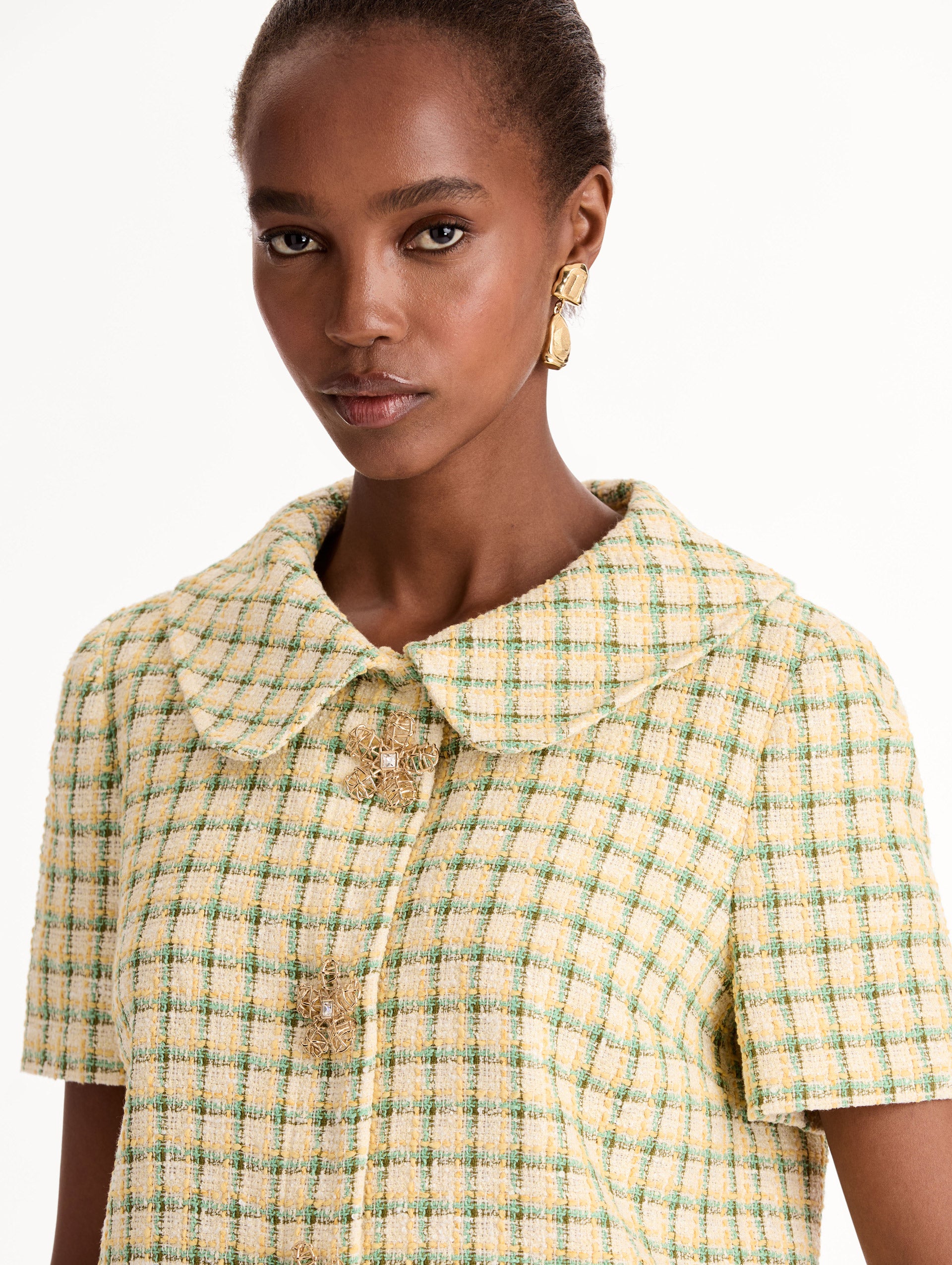 Short Sleeve Cropped Checked Tweed Jacket, Floral Button Closure, Butter Yellow with Green Checks, Rounded Collar. Close Up View.