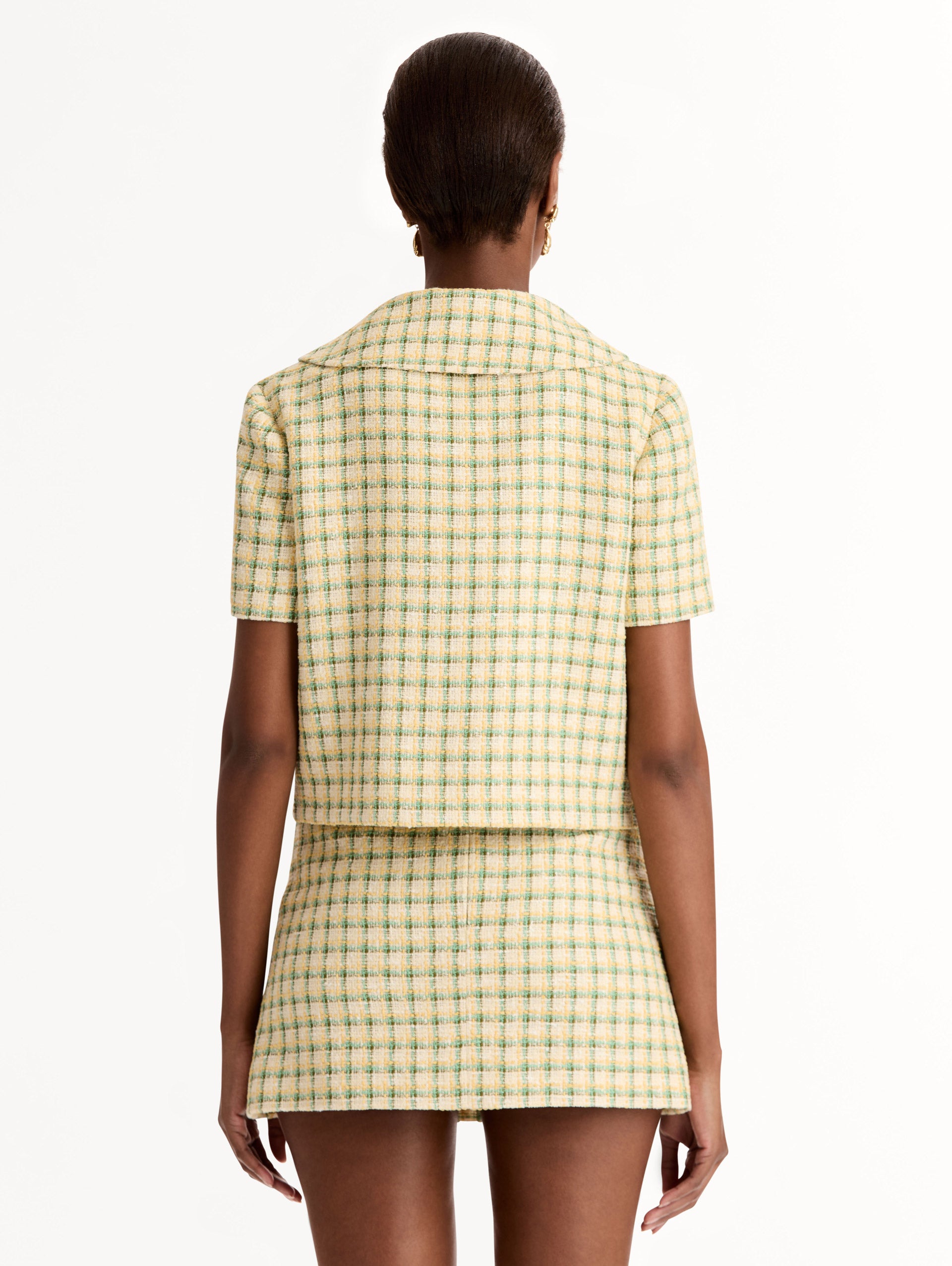 Short Sleeve Cropped Checked Tweed Jacket, Floral Button Closure, Butter Yellow with Green Checks, Rounded Collar. Back View.