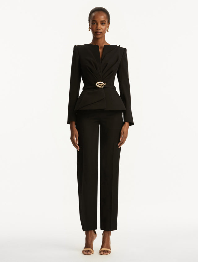 Black suiting jacket with V-neckline, long sleeves, and subtle gathering at the waist. With a sculptural gold-tone knotted belt at the waist. Front View