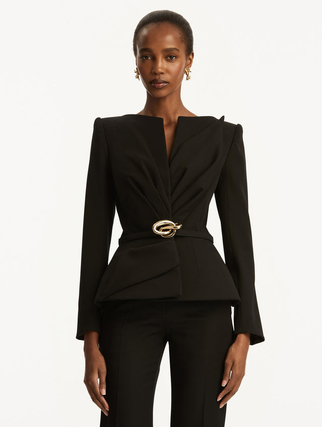 Black suiting jacket with V-neckline, long sleeves, and subtle gathering at the waist. With a sculptural gold-tone knotted belt at the waist. Front View