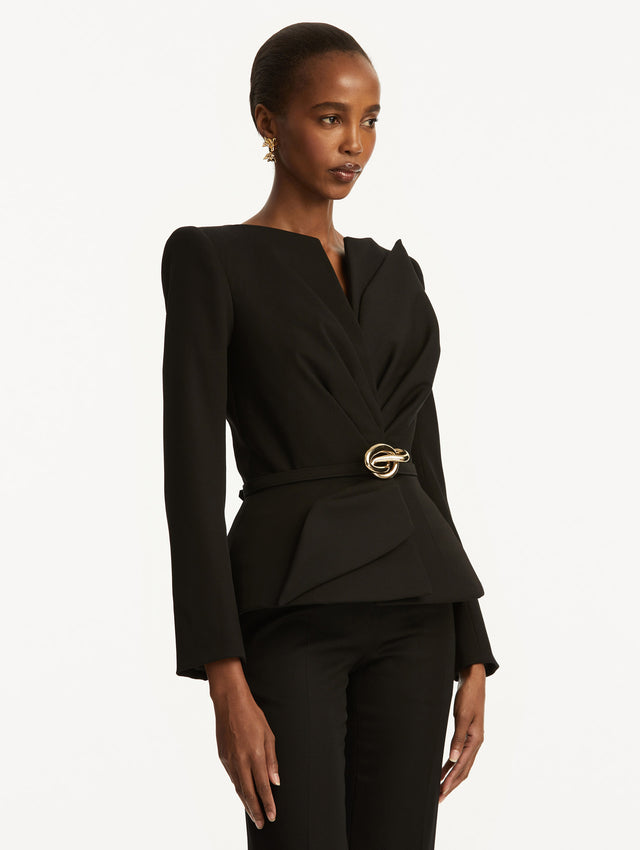 Black suiting jacket with V-neckline, long sleeves, and subtle gathering at the waist. With a sculptural gold-tone knotted belt at the waist. Side View