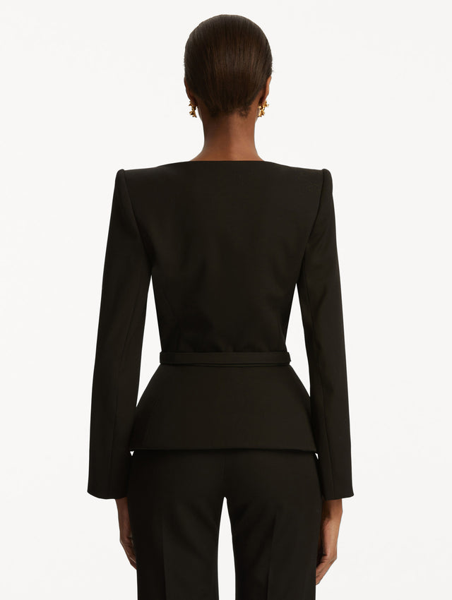 Model is wearing a Black suiting jacket with V-neckline, long sleeves, and subtle gathering at the waist. With a black belt at the waist, paired with black pants. Back View.
