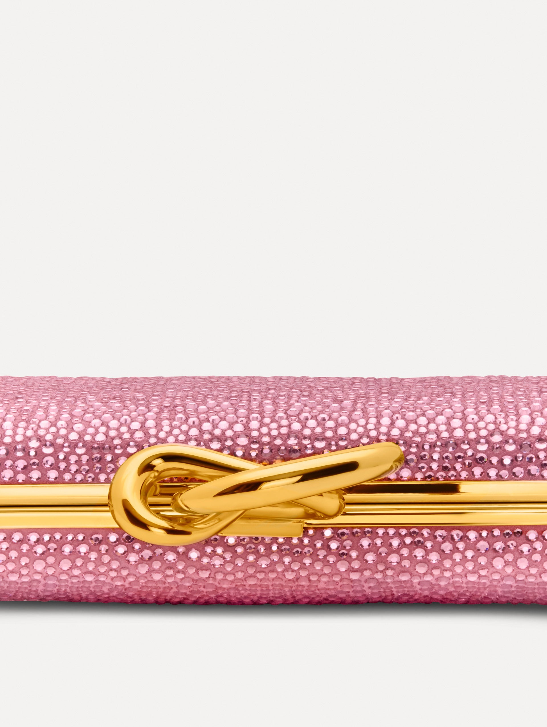 Pink Crystal Pavé Knot Minaudière featuring a rectangular silhouette, allover pavé embellishment, and sculptural gold knot clasp.